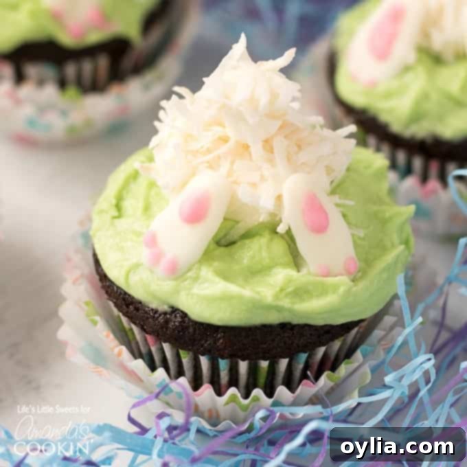 Close-up of an individual Bunny Butt Cupcake showing the detailed white chocolate feet and coconut-covered marshmallow tail nestled in green frosting.