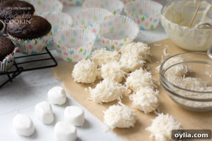 Marshmallow halves being dipped in white chocolate and then rolled in coconut flakes to create bunny bodies.