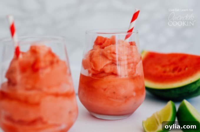 Two glasses of Watermelon Malibu Slush garnished with lime wedges and watermelon slices