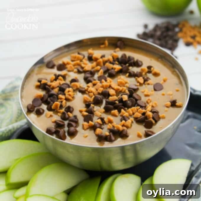 Caramel apple dip in a silver bowl with toppings