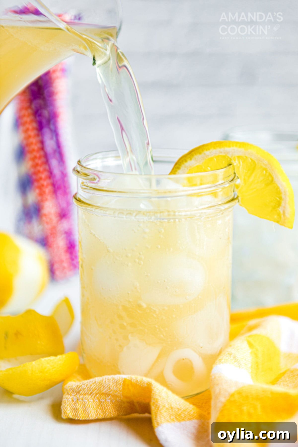 Discover the perfect Lynchburg Lemonade recipe, a smooth Jack Daniel's cocktail that's ideal for BBQs and summer gatherings. pouring Lynchburg lemonade into a mason jar glass form a pitcher