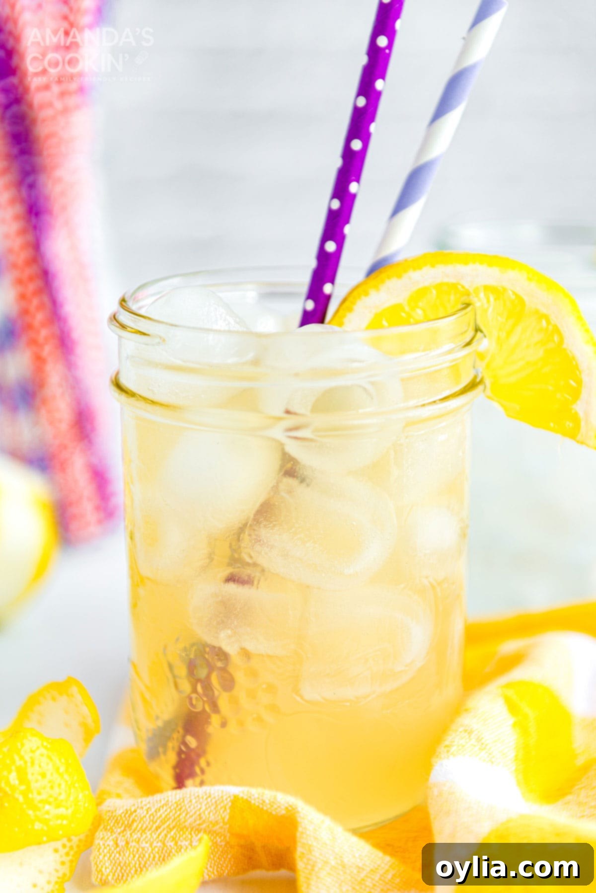 Garnish your chilled Lynchburg Lemonade with fresh lemon slices and serve with fun paper straws for a festive touch. mason jar glass of lynchburg lemonade with straws and a lemon garnish