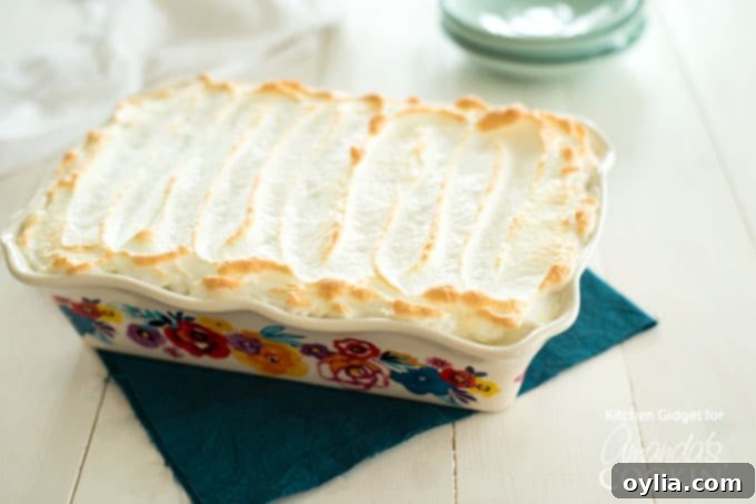 Homemade Banana Pudding with vanilla wafers visible and a golden whipped topping
