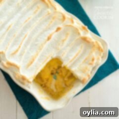 Grandma's Homemade Banana Pudding 6 A pan of homemade banana pudding with a golden meringue topping and a slice removed, showing layers