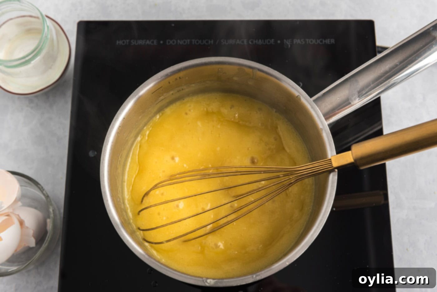 homemade lemon curd in a saucepan with a whisk