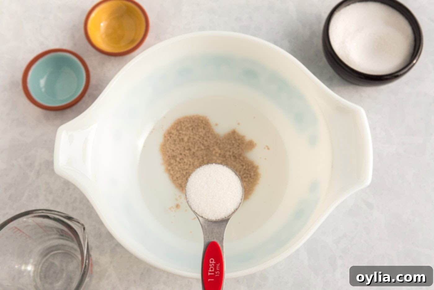 adding sugar to bowl of yeast and warm water