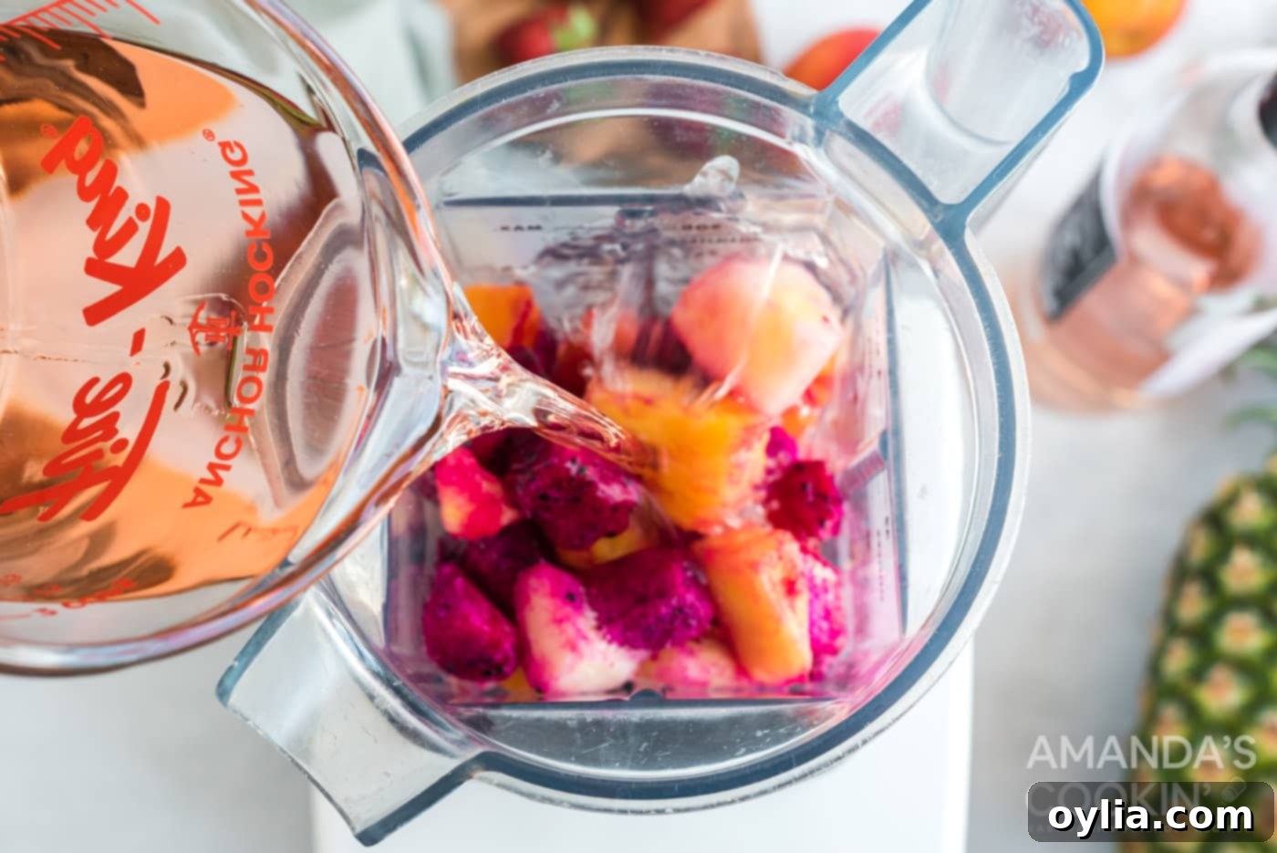 pouring rose wine into a blender with fruit