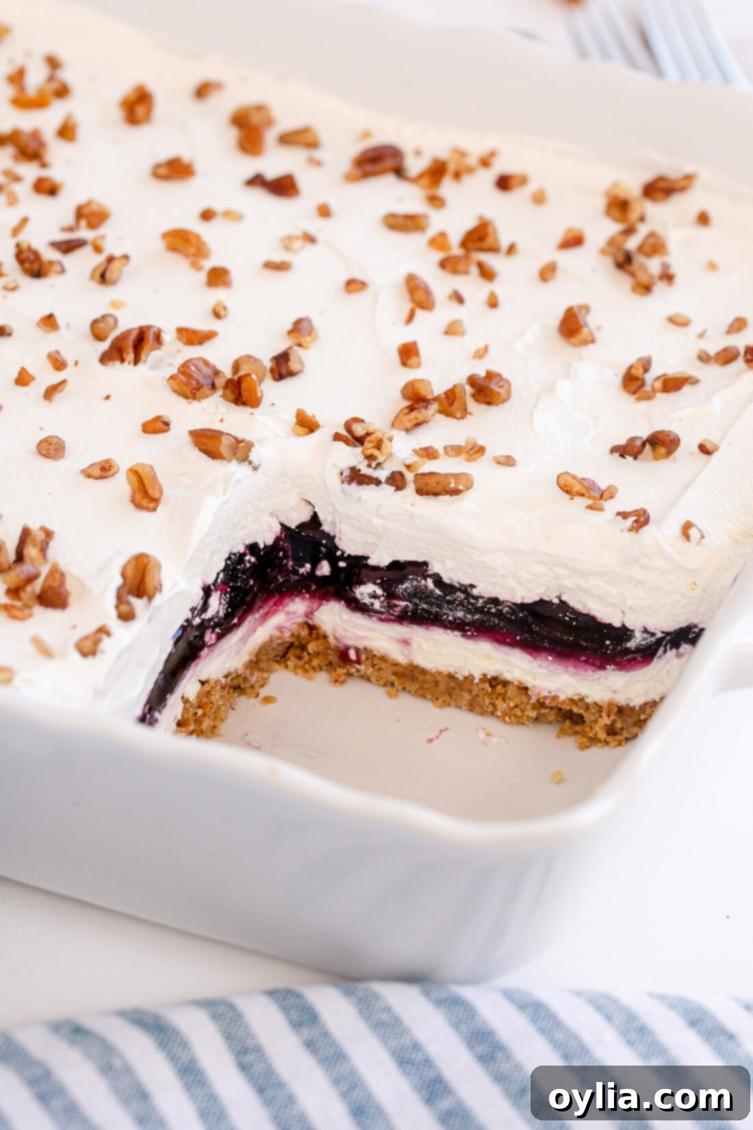 A large pan of Blueberry Delight Lush with one slice already removed, showing off the distinct, beautiful layers.