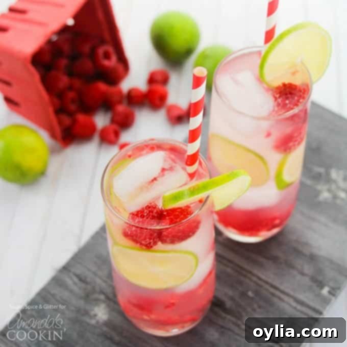 Raspberry Summer Cocktail served in a tall glass with fresh lime and raspberries