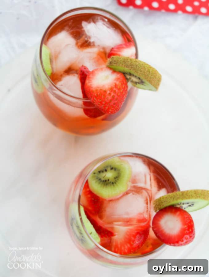 Overhead view of Strawberry Kiwi Sangria in a pitcher with sliced fruit and glasses nearby