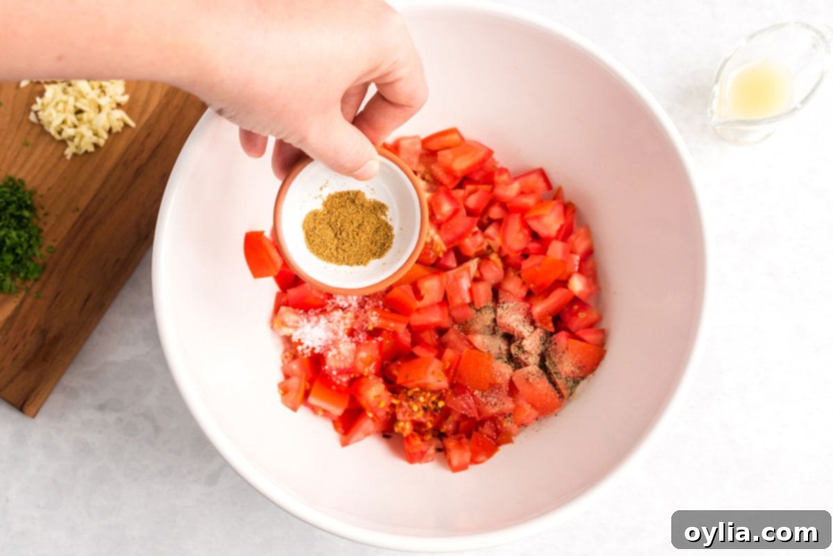 adding cumin to bowl of tomatoes