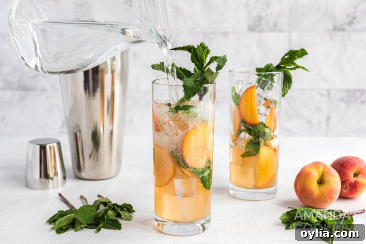 Topping a peach mojito in a tall glass with club soda, creating a refreshing bubbly finish.