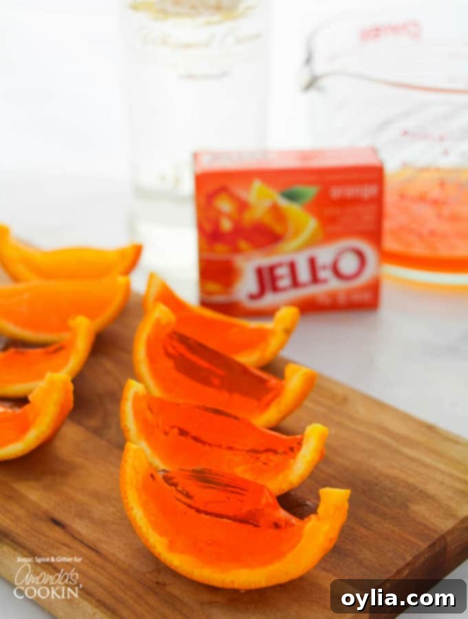 Bright orange jello shots nestled in natural orange rinds, arranged on a rustic wooden surface, perfect for a summer party.