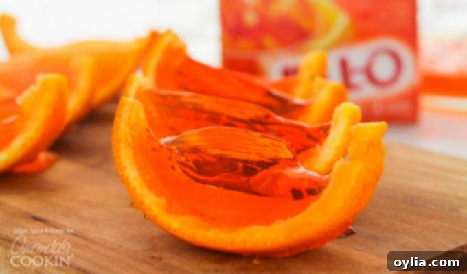A horizontal close-up of several orange jello shots in their rinds, artfully arranged and ready to serve at a gathering.