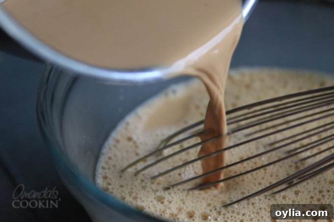 Slowly whisking hot cream mixture into egg yolks to temper them for Espresso Creme Brulee.