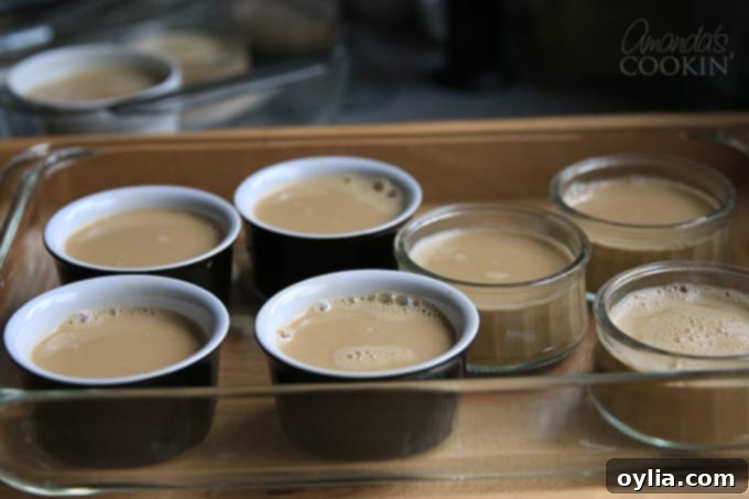 Pouring espresso creme brulee mixture into ramekins placed in a baking dish.