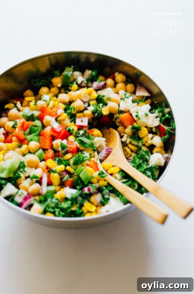 A large mixing bowl filled with sweet corn, chickpeas, and chopped vegetables, ready to be dressed.