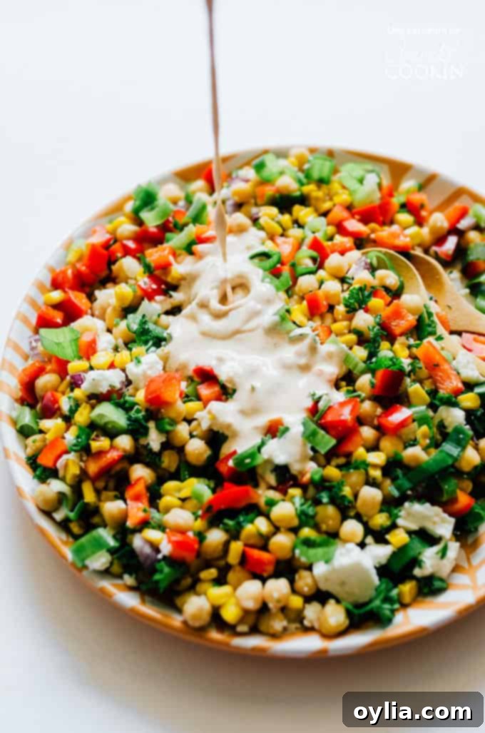 Sweet corn and chickpea salad in a serving bowl, beautifully presented with a drizzle of creamy dressing.