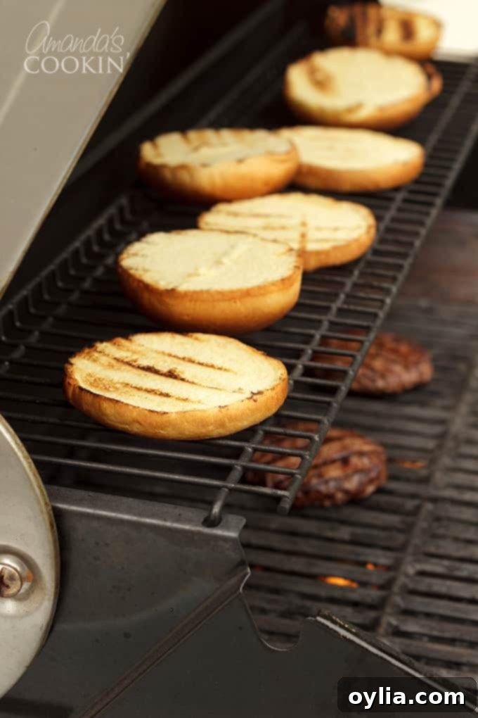Hamburger buns toasting on the grill grates.