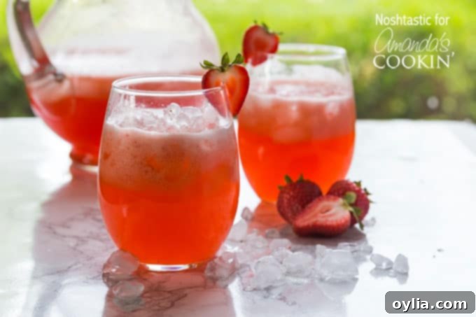 Strawberry lemonade in glasses, garnished with fresh strawberries and lime slices.