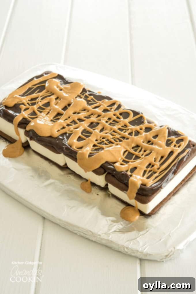 Hot fudge sauce and melted peanut butter drizzled over the first layer of ice cream sandwiches, ready for the next topping.