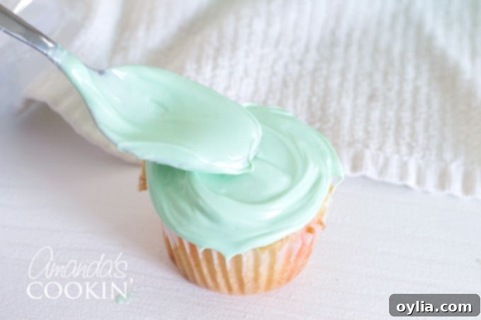 Spreading green frosting on a cupcake