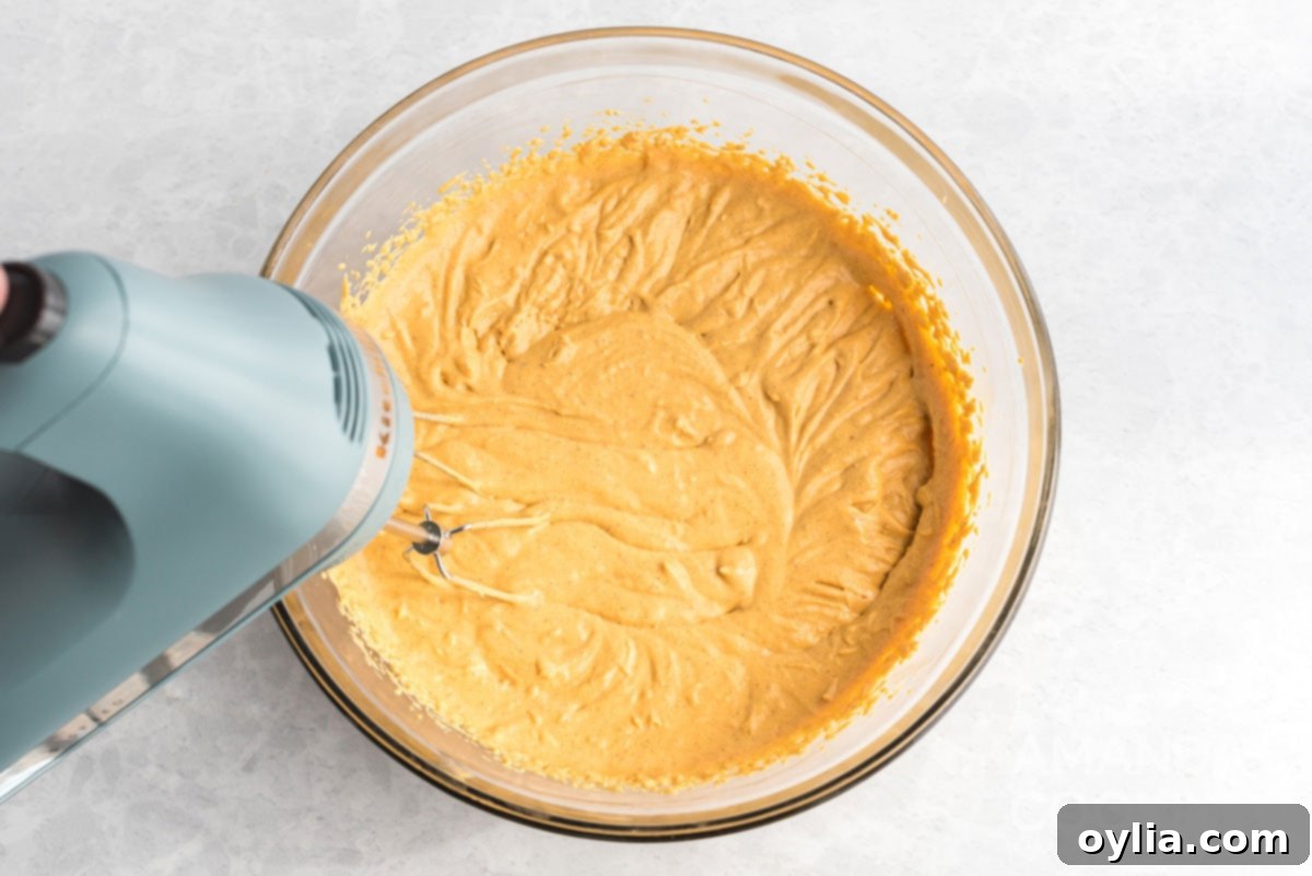 An electric mixer blending the pumpkin cheesecake ingredients into a smooth and creamy batter.