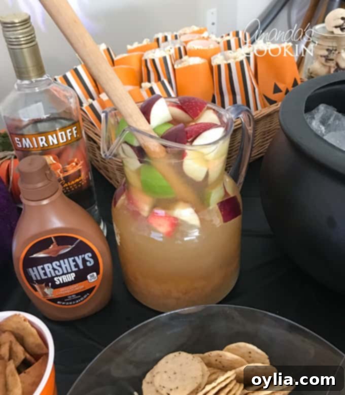 Glasses of Caramel Apple Sangria garnished with apple slices and a caramel drizzle, next to a large pitcher, for a festive fall cocktail.