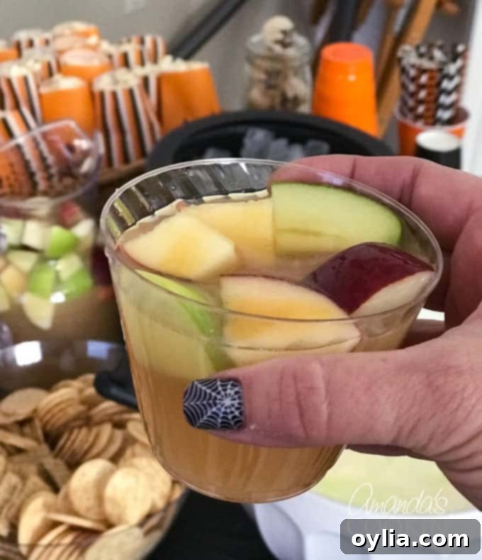 A black plastic witch's cauldron filled with ice, holding bottles for Caramel Apple Sangria, used as a festive serving container.