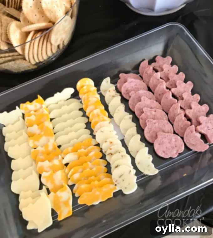 Halloween themed cheese and sausage cut into shapes like pumpkins and ghosts, ready to serve as savory party appetizers.