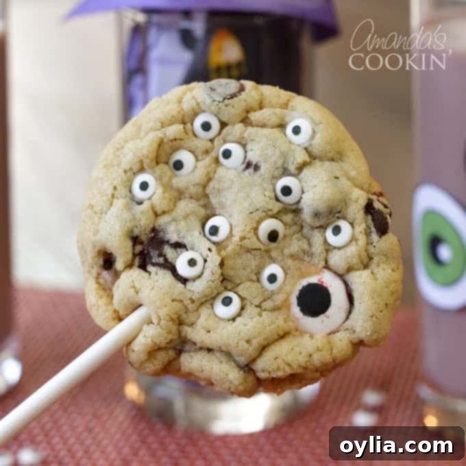Monster eyeball cookie pops on sticks, decorated with colorful frosting and candy eyes, for a spooky-cute Halloween treat.