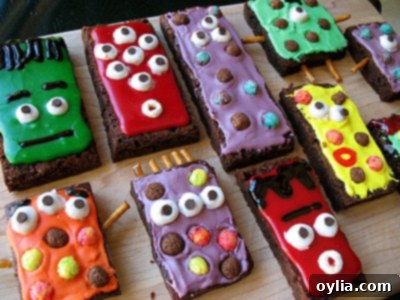 Colorful monster brownies decorated with vibrant frosting, candy eyes, and sprinkles, served on a plate for a Halloween party.