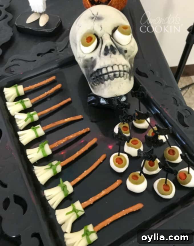 Platter of pretzel broomsticks made with string cheese and pretzel sticks, alongside mozzarella eyeballs for a spooky Halloween appetizer spread.