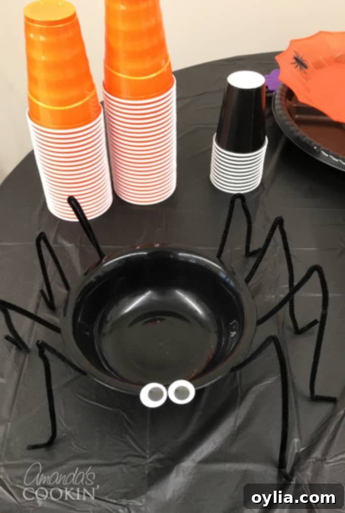Close-up of a DIY spider bowl with pipe cleaner legs, filled with hummus, ready for a Halloween party.