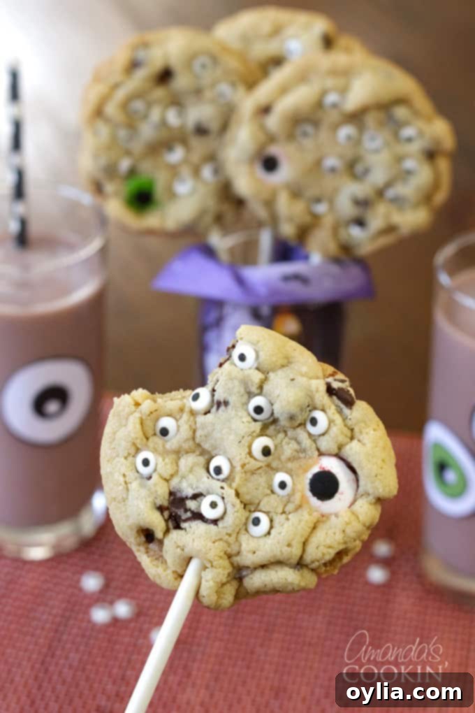 Monster Eyeball Cookie Pops with a bite taken out, served with decorated chocolate milk
