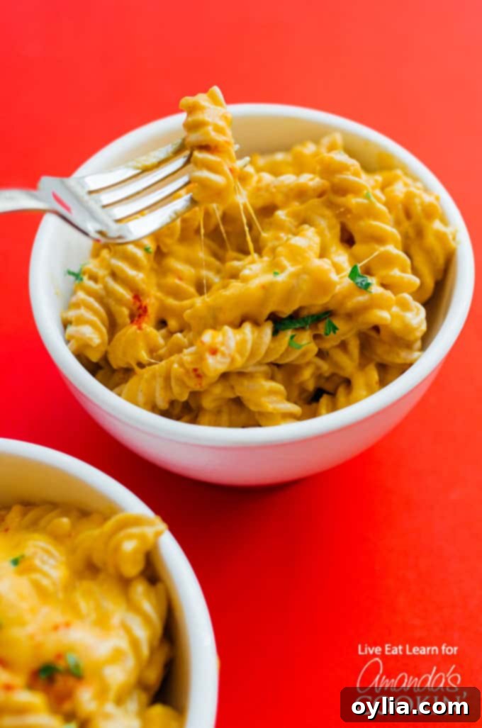 Butternut Squash Macaroni and Cheese served in a rustic white bowl, garnished with fresh parsley and a sprinkle of paprika, on a wooden surface.