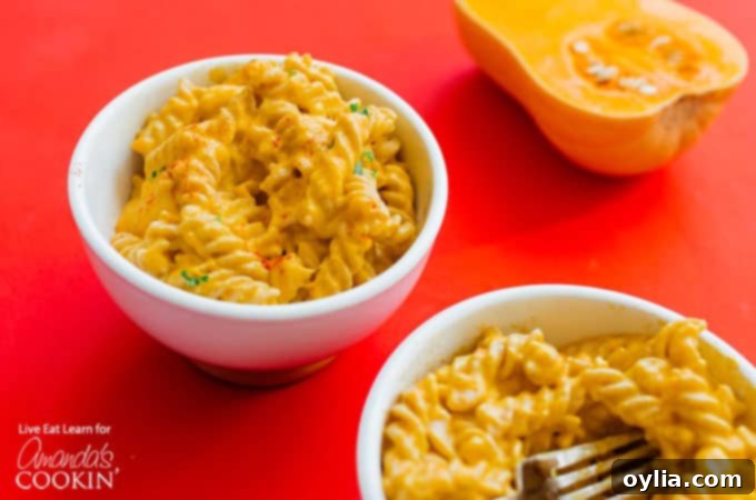 Two bowls of Butternut Squash Mac and Cheese horizontally arranged on a wooden table, ready for a delicious meal.