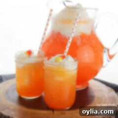 two glasses of candy corn punch with pitcher in background
