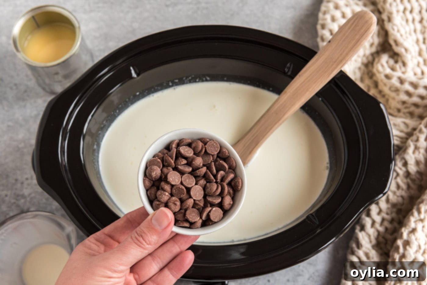 adding chocolate chips to crockpot with heavy cream and sweetened condensed milk