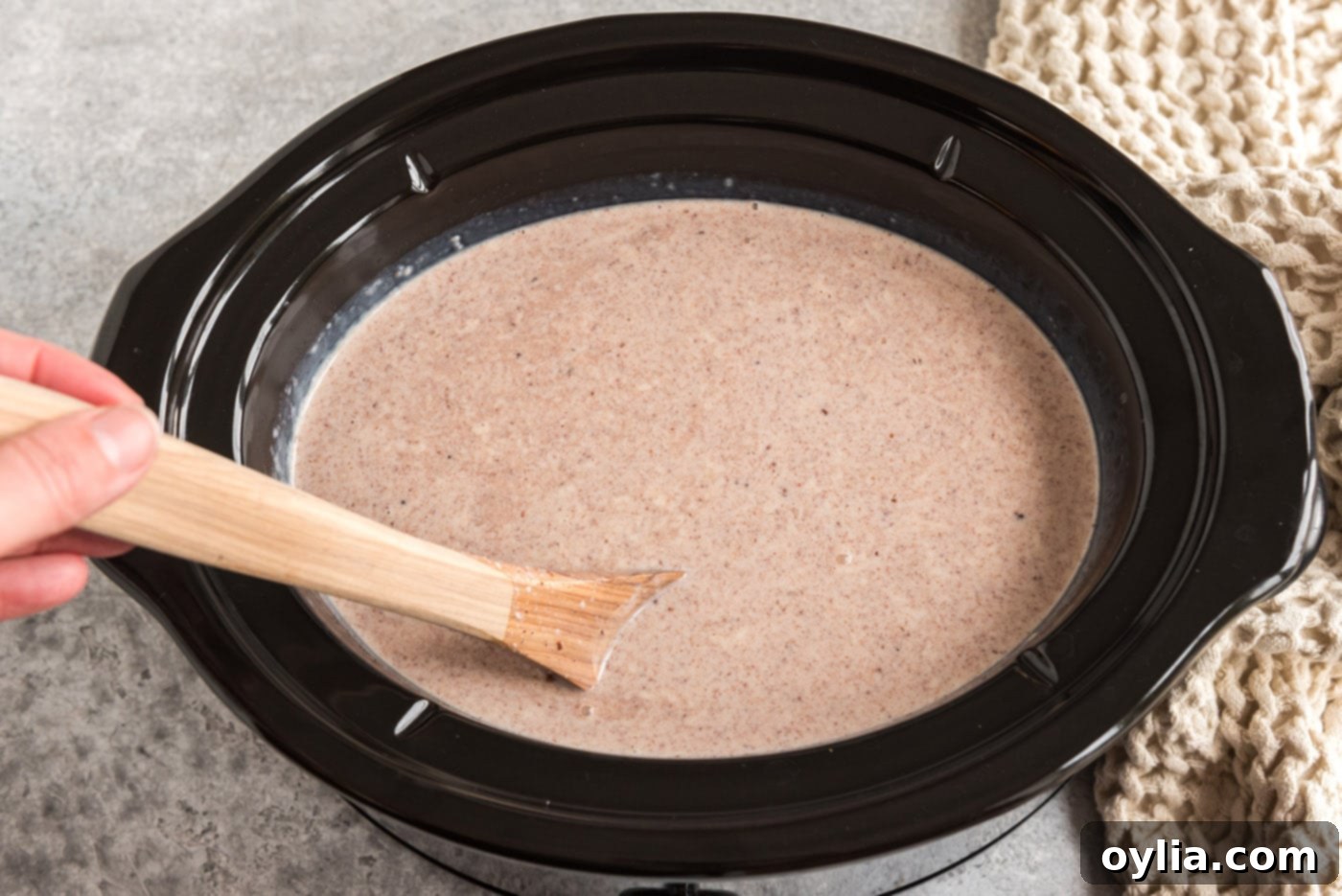 stirring crockpot hot chocolate with a wooden spoon