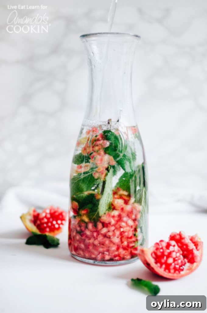 Ingredients for Holiday Detox Drink – mint, pomegranate, water, and honey – in a pitcher, ready to be mixed