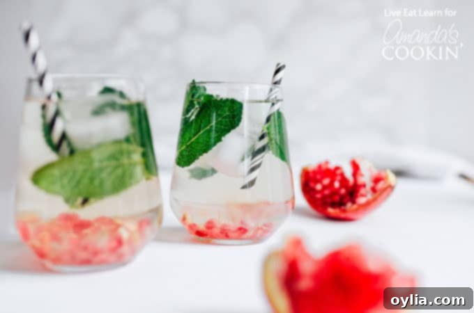 Several glasses of Holiday Detox Drink garnished with mint and pomegranate seeds, on a festive table setting