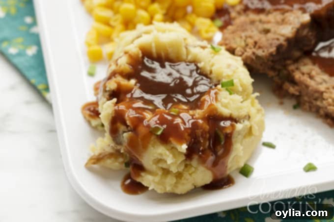 These Crockpot Mashed Potatoes have the skin on, but you can peel them if you want to. Making mashed potatoes in the slow cooker is perfect for the holidays! #crockpotmashedpotatoes #slowcookermashedpotatoes #mashedpotatoes #thanksgivingrecipes #potatoes #chickenbroth #garlic #sourcream #creamcheese Close-up of fluffy and creamy mashed potatoes