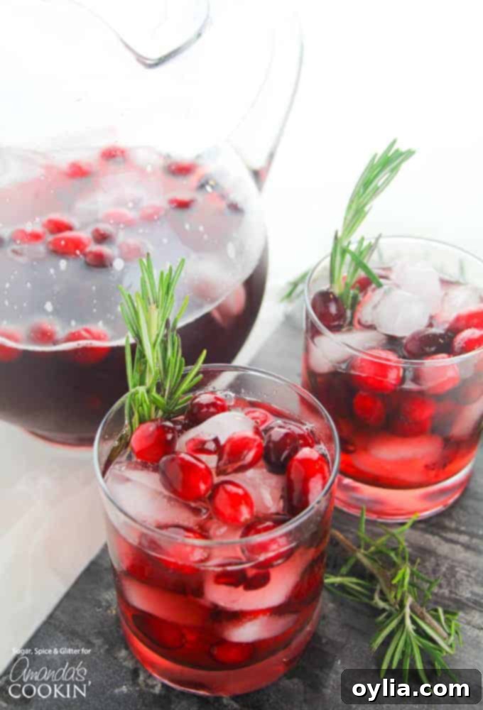 Glasses of festive Cranberry Holiday Punch, garnished with cranberries and orange slices, perfect for seasonal parties.