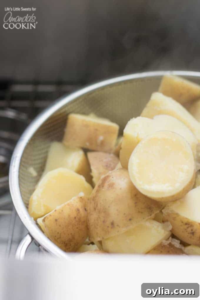 Cut and cooked Yukon Gold potatoes steaming in a colander