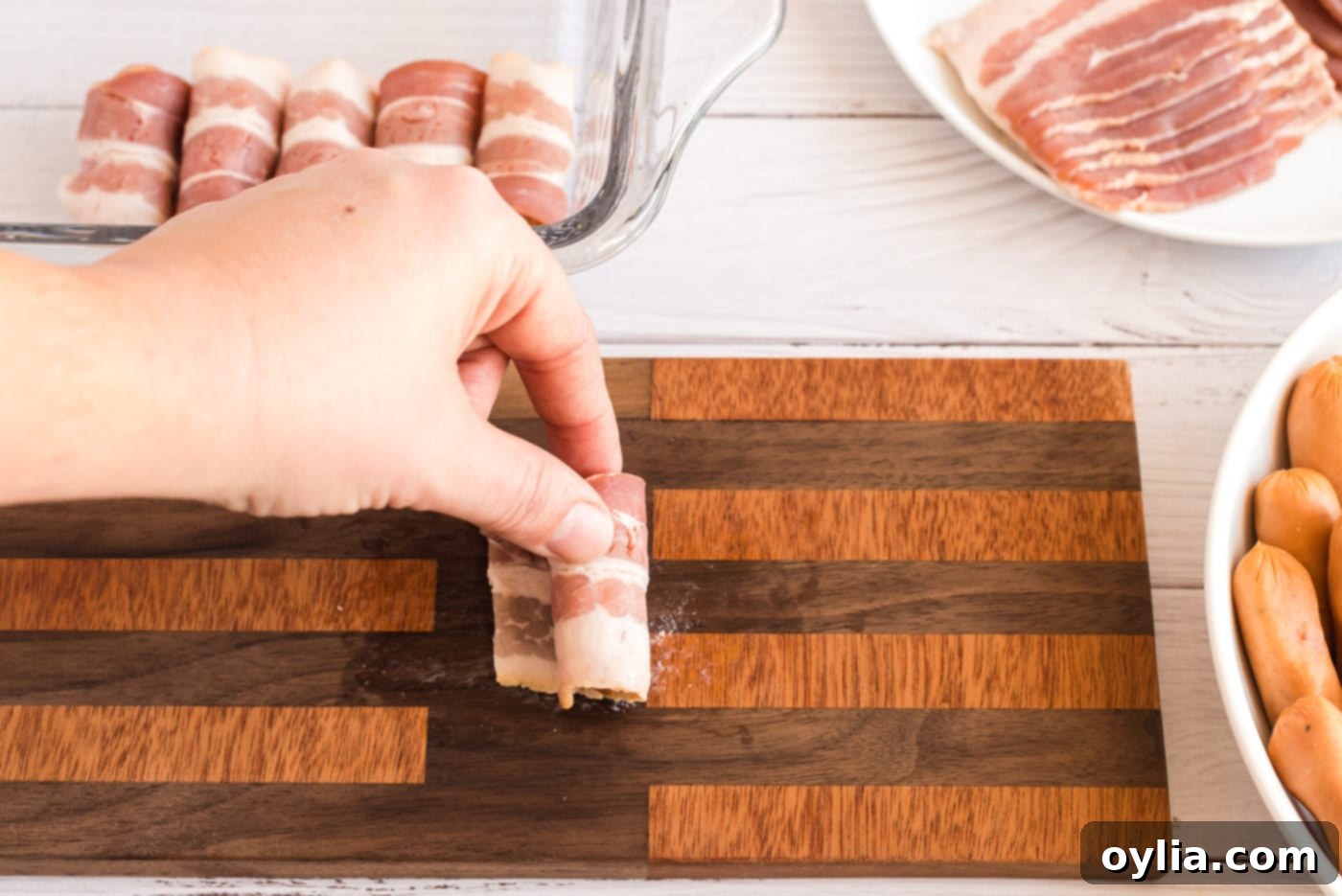 Wrapped sausage in bacon placed seam down in a baking dish