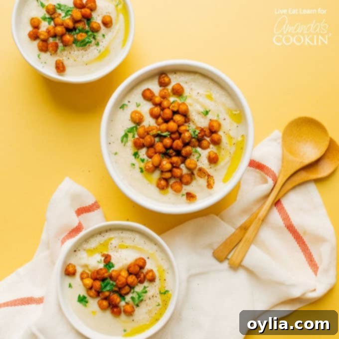 Three bowls of creamy cauliflower soup garnished with roasted chickpeas