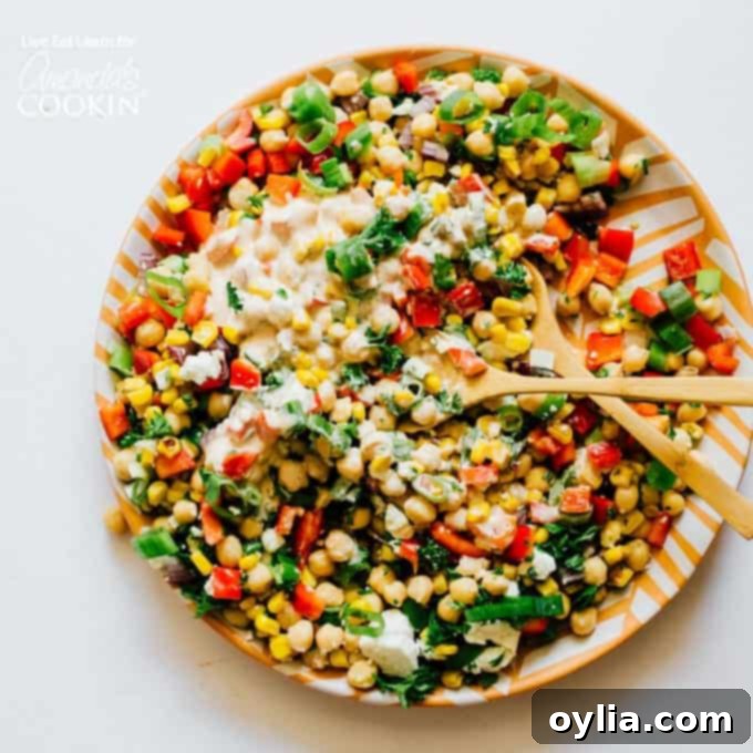 Colorful sweetcorn and chickpea salad on a plate with serving spoons