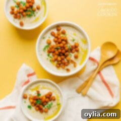 Three bowls of creamy cauliflower soup garnished with roasted chickpeas