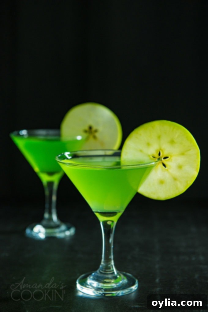 two appletini martinis on a dark background garnished with apple wheels